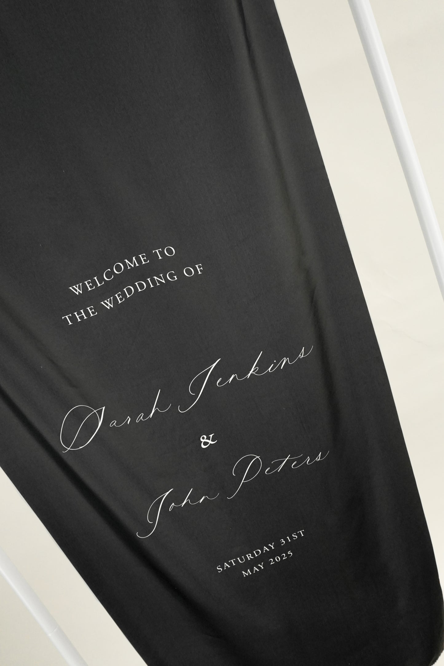 Black silk wedding welcome sign with white text on a white surface