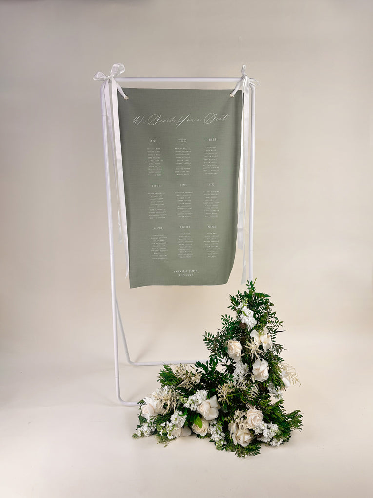 Sage green seating chart with floral arrangement on a white background