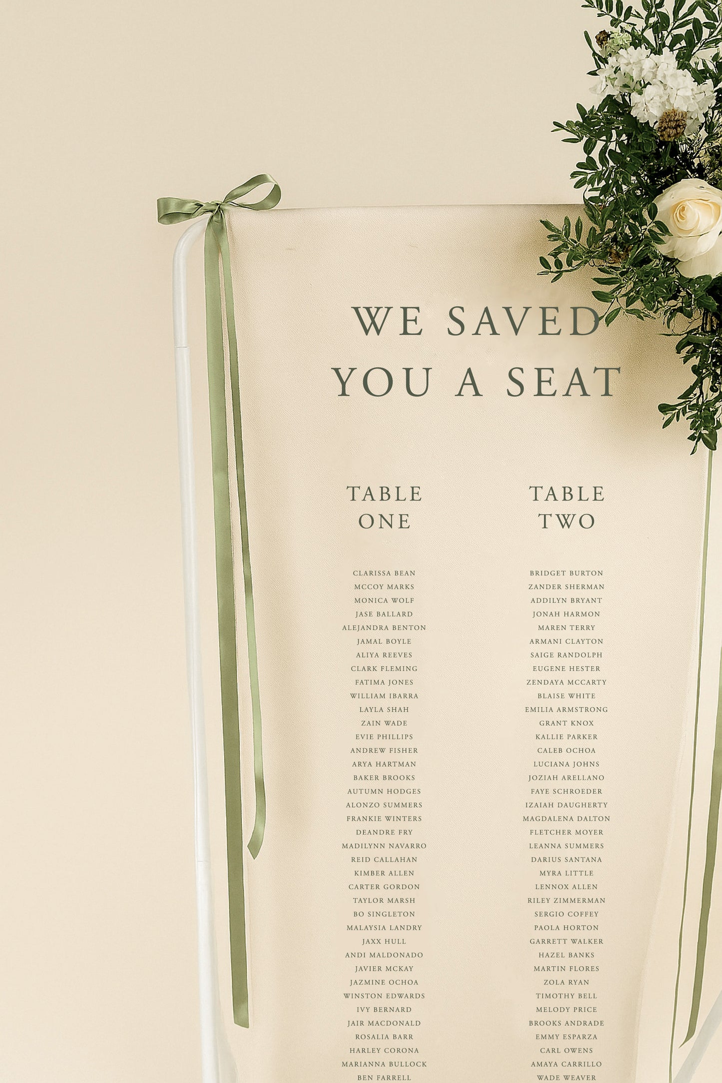 Wedding seating chart with 'We Saved You a Seat' text, table assignments, and decorative elements.