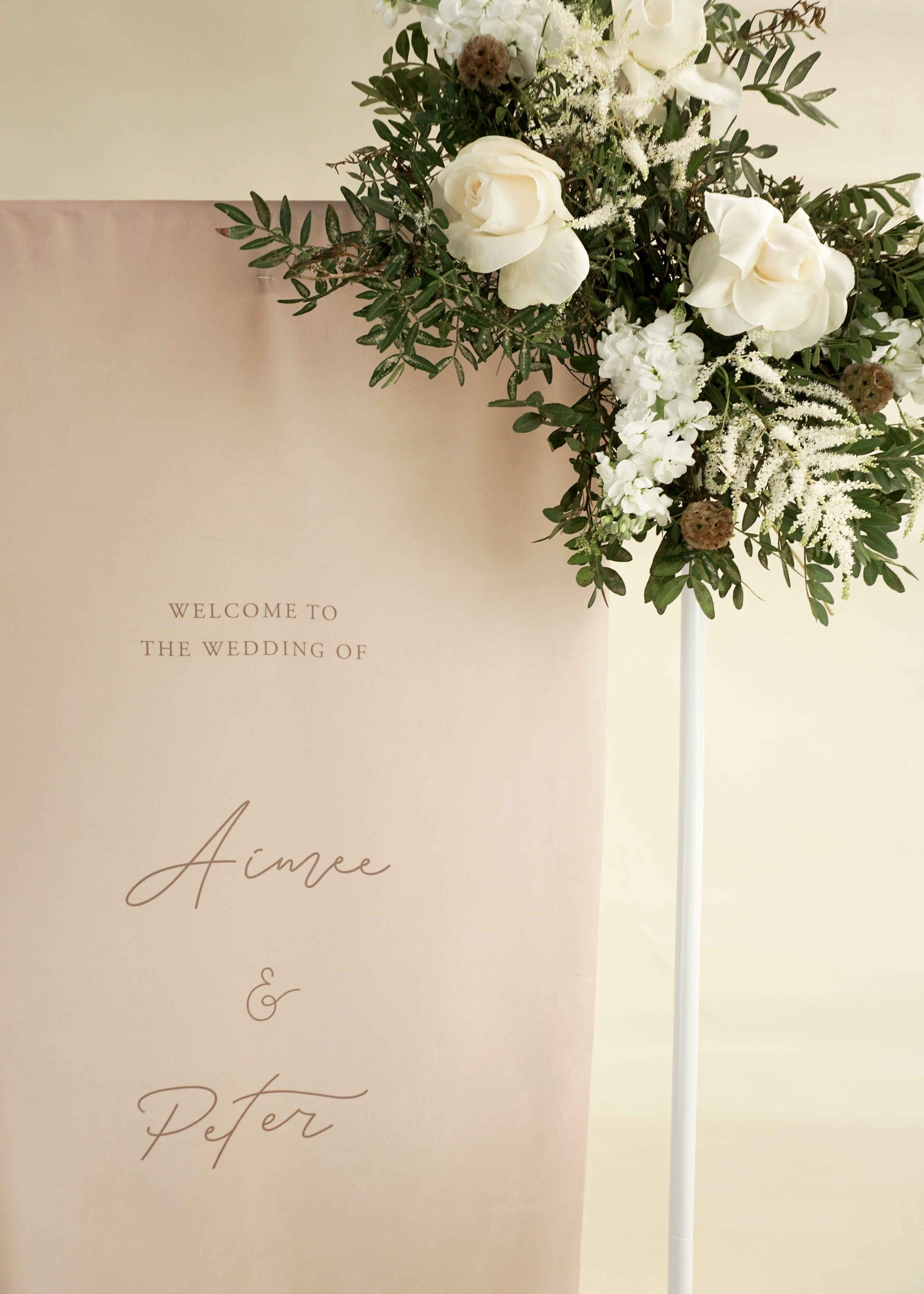 Decorative floral arrangement with a welcome wedding sign on a beige background