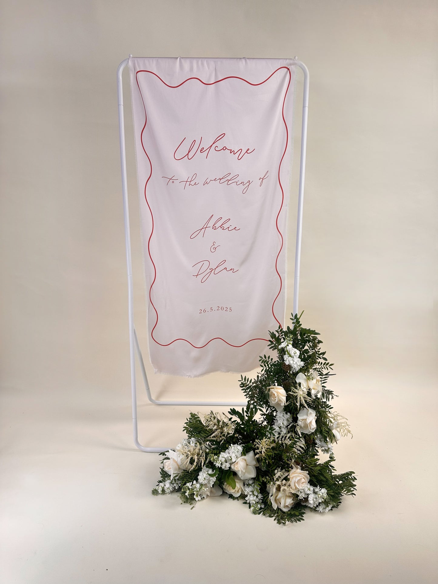 Decorative welcome sign with floral arrangement on a pink background
