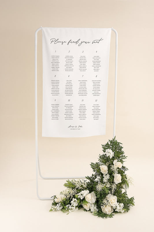 Seating chart on a stand with floral decoration against a beige background