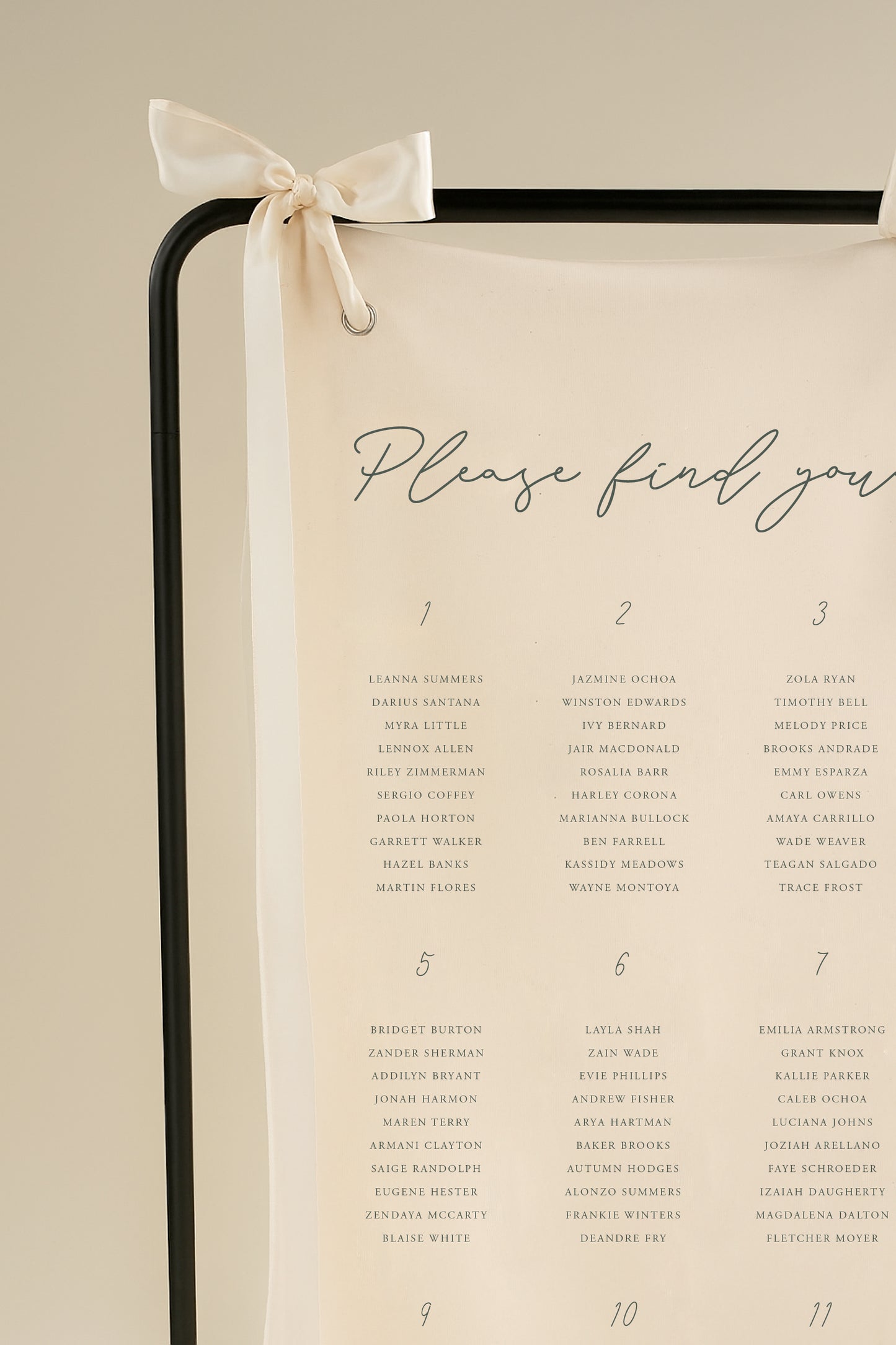 Seating chart with names on a beige background, tied with a ribbon.