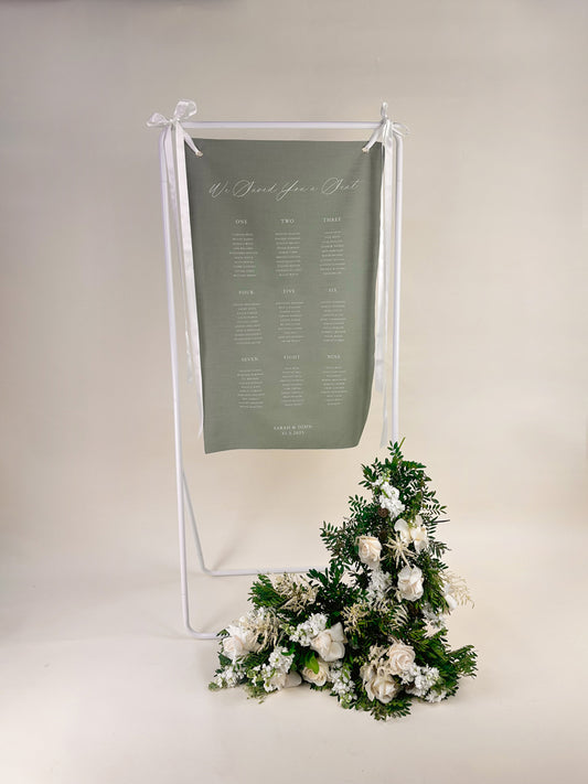 Sage green seating chart with floral arrangement on a white background