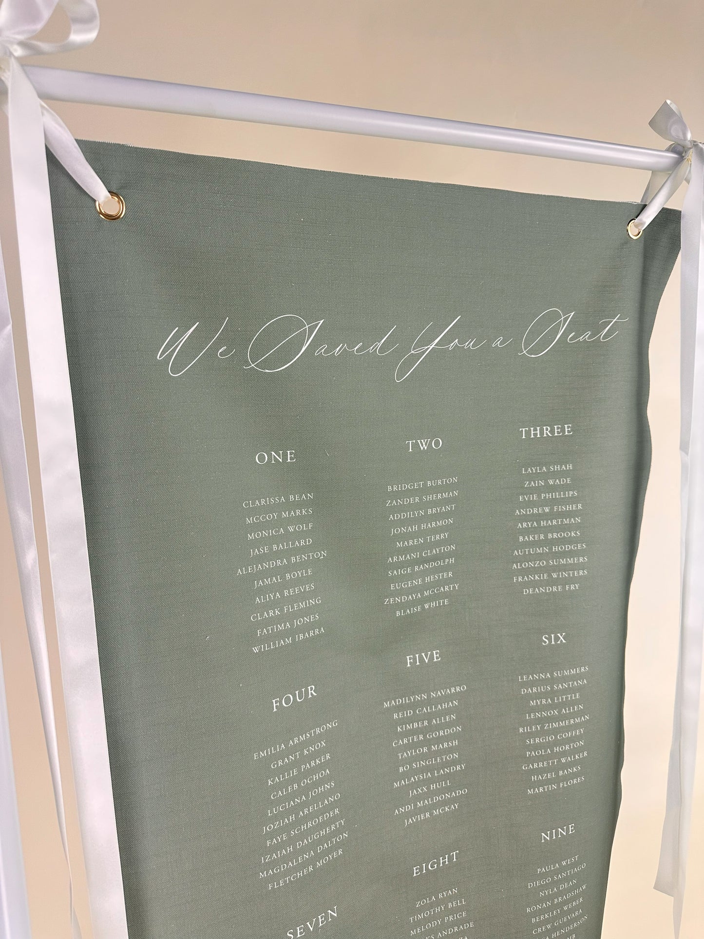 Green fabric with white text and 'We Saved You a Seat' printed on it, hanging from a stand.