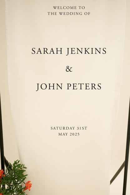 Wedding invitation with text 'Welcome to the wedding of Sarah Jenkins & John Peters' on a beige background.