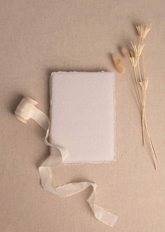 5x7 inch Beige Handmade paper sheet with deckle edge surrounded by dried flowers and cream silk ribbon spool